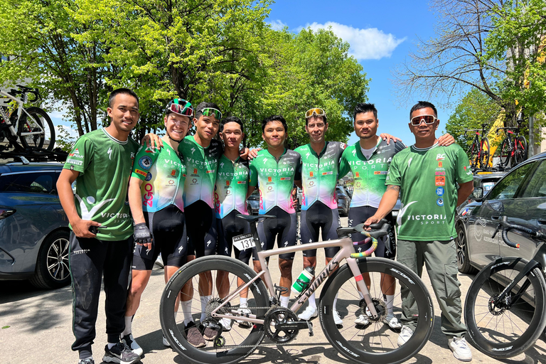 Six Victoria riders flanked by two staff members pose for a picture behind one of the team's S-Works bicycles.
